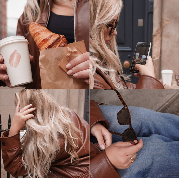 Vertical stock photo of woman walking on city street with sunglasses, coffee, and iPhone, faceless content aesthetic.